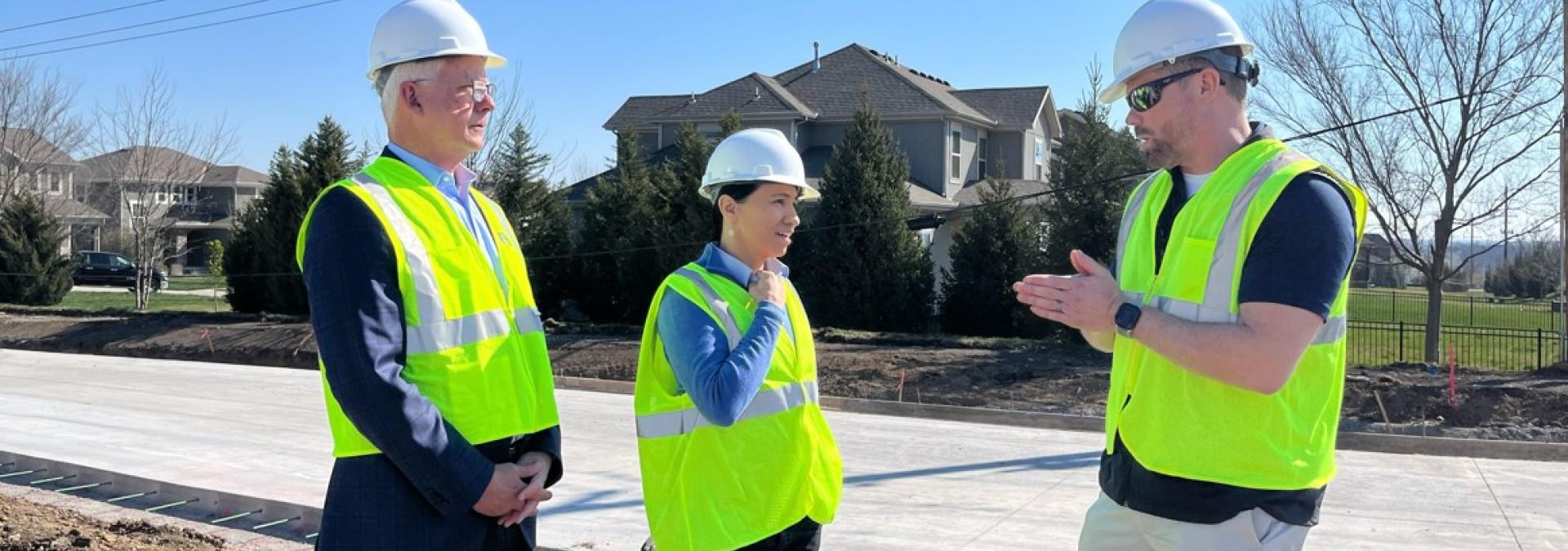 Rep. Sharice Davids, Mayor Curt Skoog, and Project Manager Brent Gerard standing beside a soon-to-be roundabout on 167th Street.