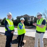 Rep. Sharice Davids, Mayor Curt Skoog, and Project Manager Brent Gerard standing beside a soon-to-be roundabout on 167th Street.