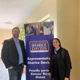 Rep. Sharice Davids stands in front of a sign with her office's logo