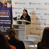 Rep. Sharice Davids speaking at a podium at Vibrant Health in Kansas City, Kansas.