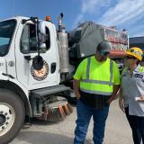 Sharice Davids and a Wyandotte County maintenance staff member stand next to a street sweeper