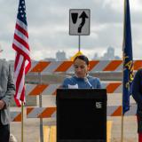 Sharice Davids standing outdoors at podium with two people behind her