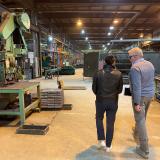 Two people walking into a manufacturing facility away from the camera