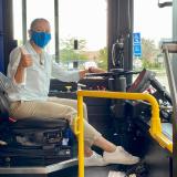 Sharice Davids in the drivers seat of a bus giving a thumbs up