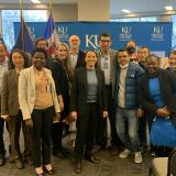 Group of people in front of flags and KU backdrop