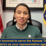 Rep Davids seated in front of an American flag and a Kansas flag