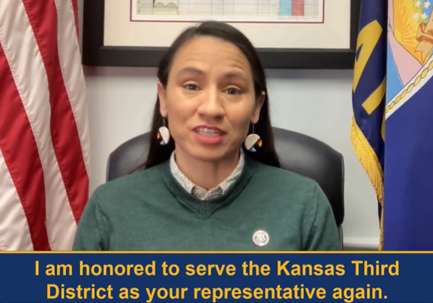 Rep Davids seated in front of an American flag and a Kansas flag