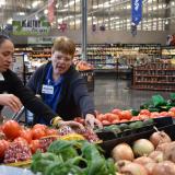 Rep. Sharice Davids assists a Price Chopper employee in restocking tomatoes in the produce section.