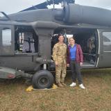 Two people in front of a helicopter, one in army fatigues