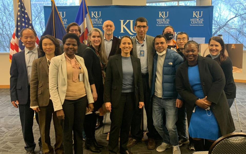 Group of people in front of flags and KU backdrop